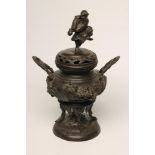 A JAPANESE BRONZE CENSER, the low domed lift-off cover surmounted by a warrior, the squat globular