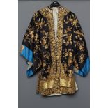 A CHINESE BLACK SILK COAT, the sleeves with blue "cuffs", whipped in gold coloured thread with