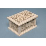 AN IVORY CASKET of plain oblong form, the hinged cover carved with scrolling foliage enclosing an