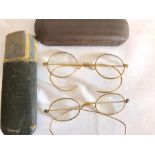 Two yellow metal rimmed spectacles in cases.