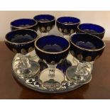 Seven blue glass goblets on mirror tray