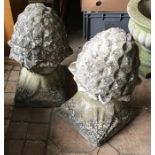 Two reconstituted stone pineapples on stands. 63cms h.