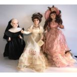 Three good quality modern porcelain headed dolls included a nun. Middle seated on stool. H - 58cms.