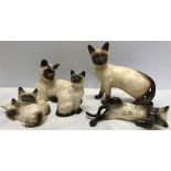 Three Royal Doulton Siamese cat figurines and 2 Beswick, 1 mat finish and a goblet cat.
