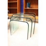 A NEST OF THREE SOLID GLASS TABLES, Mid Century Modern style, each formed from a single curved sheet