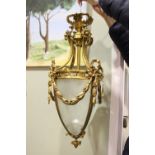 AN ACORN SHAPED HANGING GLASS LANTERN, with frosted glass panels and gilt metal frame, having swag