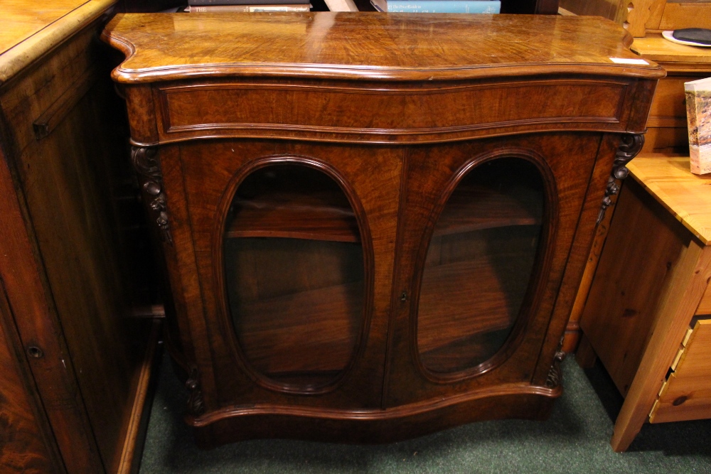 19TH CENTURY WALNUT SERPENTINE FRONTED TWO DOOR CABINET, with oval glazed doors beneath single