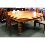 AN EXTENDABLE DINING TABLE, raised on baluster shaped legs, decorated with carved and fluted detail,