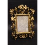 A TABLE TOP GILT FRAME / MIRROR, with raised foliage decoration, 12" x 8" approx frame