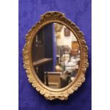 A GILT METAL OVAL WALL MIRROR, with ripple collar detail & foliage detail, 18" x 14" approx