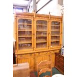 AN EARLY 20TH CENTURY OAK 3 DOOR GLAZED BOOKCASE, with brass details and carved and turned column