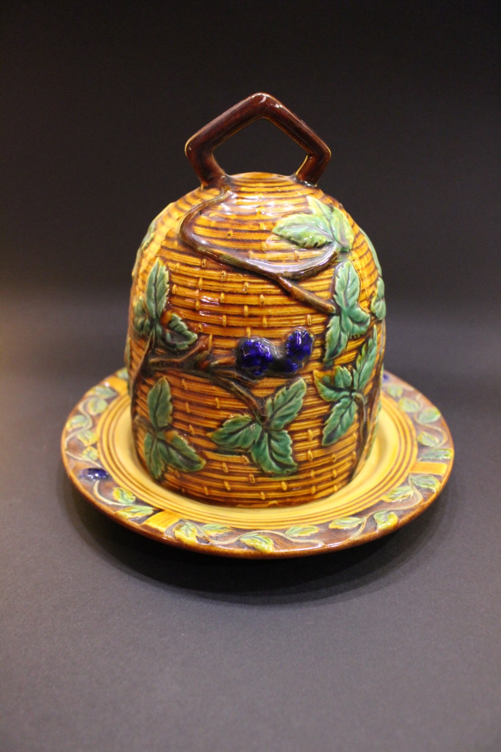 A MAJOLICA STYLE CHEESE DOME, with basket weave design, and berry & leaf decoration, 6.5" tall and