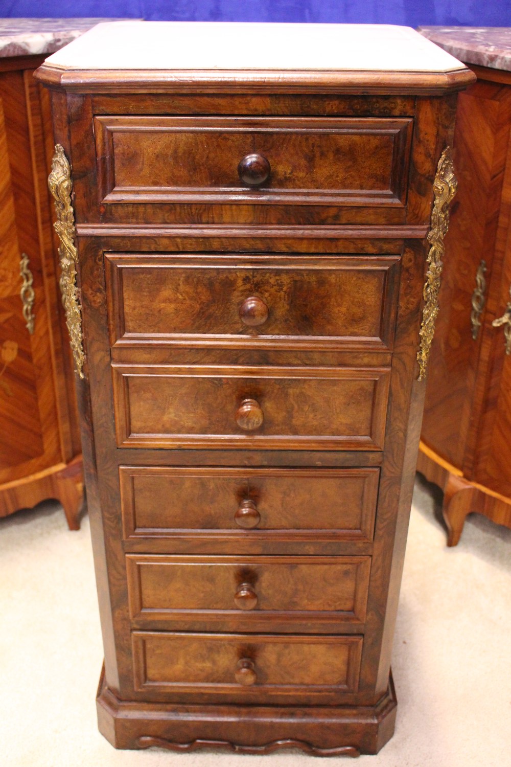A MARBLE TOPPED CABINET, with canted corners, the front with ormolu mounts, 1 drawer over a drop