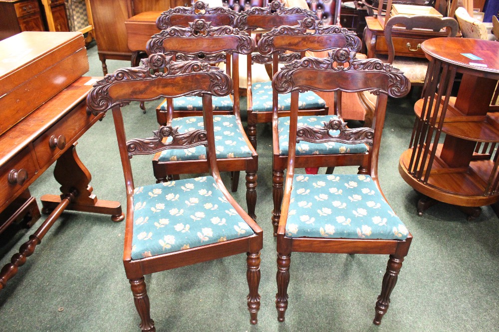 A SET OF 6 MAHOGANY REGENCY DINING ROOM CHAIRS, with lift up seats, and carved rose motif backs,