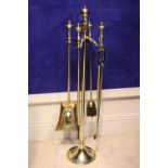 A SET OF VICTORIAN BRASS FIRE IRONS on a stand, includes shovel, poker, tongs & brush, stand is