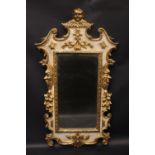 A GILTWOOD WALL MIRROR, with winged cherub head pediment, faces & fruit branch decoration to the