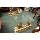 A LOW RISE GLASS TOPPED COFFEE TABLE, raised on a pair of gilt Sphinx supports on rectangular bases,