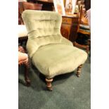 A BUTTON BACKED LOW RISE 'NURSING' CHAIR, with turned front leg, green velvet upholstered cover, 30"