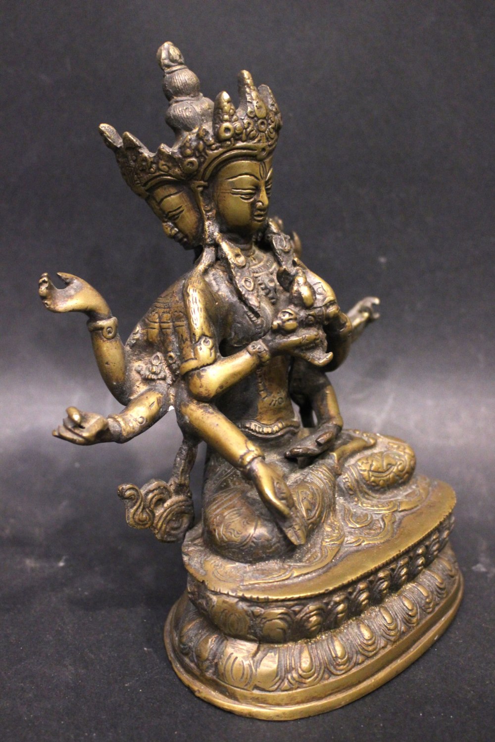 A BRASS FIGURE OF THE BUDDHIST DIETY USHNISHAVIJAYA, with three heads and 8 arms, sitting in the - Image 2 of 3