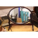 A TABLE TOP SWING MIRROR, oval in shape, raised on shaped upright supports, 21" x 18" x 8" approx