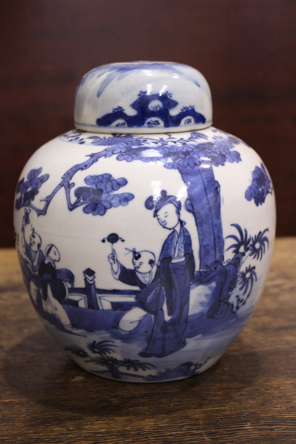 A BLUE & WHITE GINGER JAR with lid, decorated with images of children and a woman playing in a