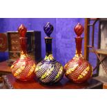 THREE BOHEMIAN STYLE GLASS DECANTERS, with stoppers, 2 x red with gilt and painted detail, 1 x