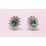 A PAIR OF 18CT WHITE GOLD COLOMBIAN EMERALD & DIAMOND CLUSTER EARRINGS