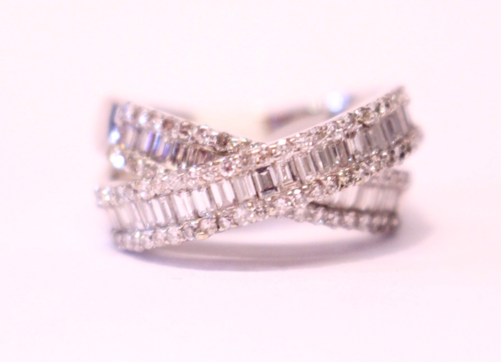 AN 18CT WHITE GOLD DIAMOND CROSS OVER RING, with baguette and round brilliant cut diamonds, 2.10cts