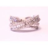 AN 18CT WHITE GOLD DIAMOND CROSS OVER RING, with baguette and round brilliant cut diamonds, 2.10cts