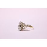 AN EDWARDIAN STYLE TWO DIAMOND RING, with leaf shaped mount having paved diamonds to it, main