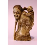 A CARVED NETSUKE OF A BEARDED MAN HOLDING A CHILD ON HIS SHOULDER, with a staff in his right hand,