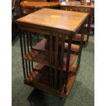 AN INLAID MAHOGANY REVOLVING BOOKCASE, with central inlaid floral detail to the top, on castors, 34"