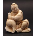 A CARVED NETSUKE OF A SITTING MAN, HOLDING A CONCH SHELL, 1.75" approx height