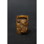 A CARVED NETSUKE OF FROGS ON A WELL BUCKET, with a character mark beneath, 2" x 1.25" x 1" approx