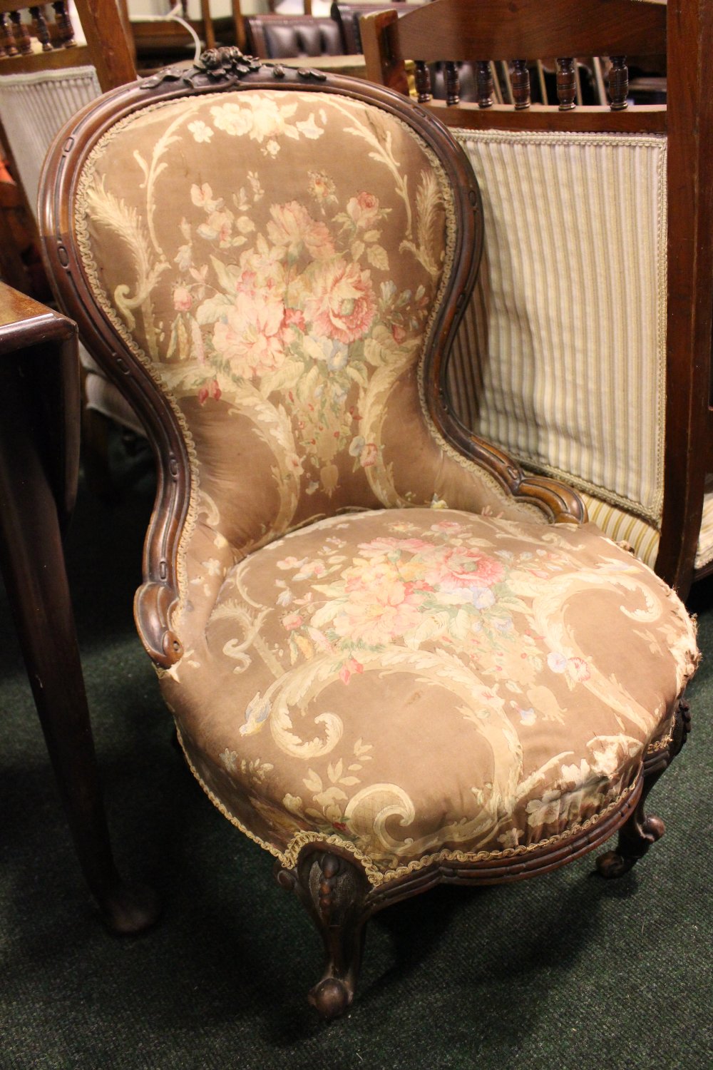 A LOW RISE BEDROOM / NURSING CHAIR, with carved rose detail to the frame, raised on short cabriole