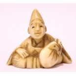 A CARVED NETSUKE OF A MAN IN A POINTED HAT, 1.25" tall, 1.5" long, .75" deep approx