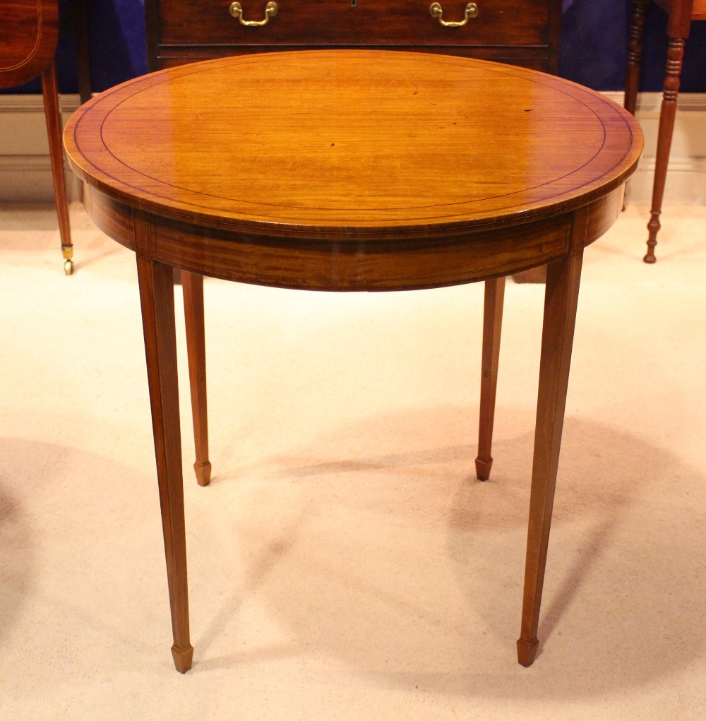 AN EDWARDIAN SATINWOOD CIRCULAR CENTRE TABLE, with ebonised inlaid detail, raised on tapered spade