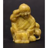 A CARVED NETSUKE OF A SEATED MAN, with rodents climbing about him, 2.75" approx height