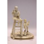 A JAPANESE CARVED FIGURAL GROUP, a man on a stool with a boy standing to his side, 6.75" tall approx