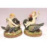 A PAIR OF MANTLE ORNAMENTS, in the form of cupids sitting upon ducks on a floral ground, each 9.5" x
