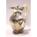 AN EARLY 19TH CENTURY SILVER PITCHER, with hinged lid having floral finial, the body decorated