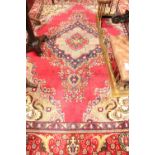 A PERSIAN HAND KNOTTED FLOOR RUG, with main ground burgundy red, having a large central medallion,