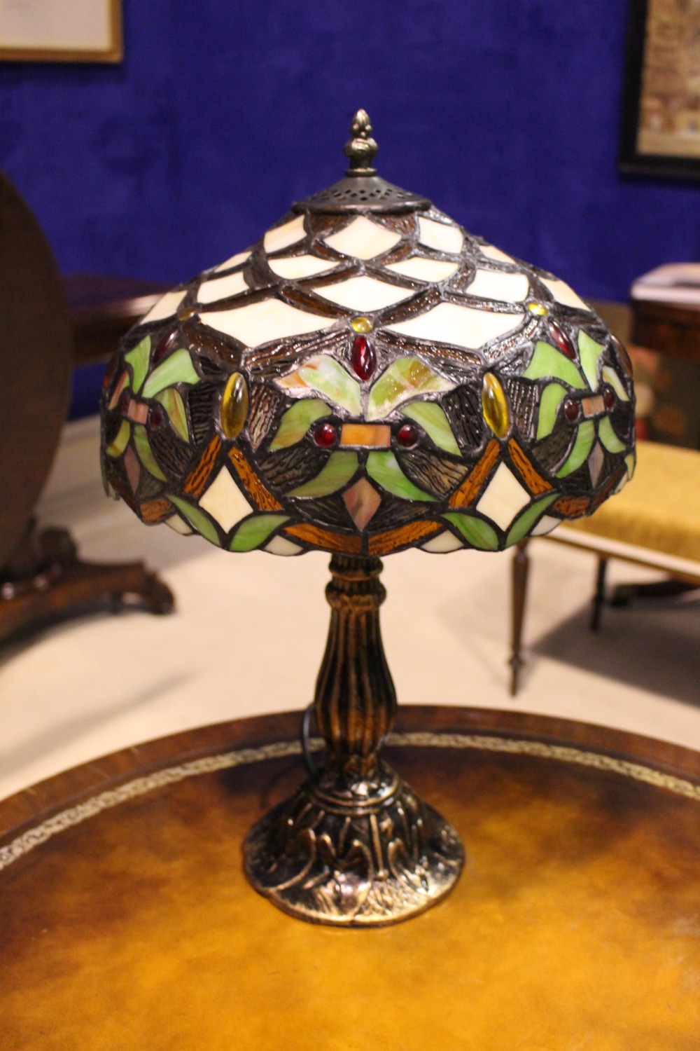 A TIFFANY STYLE TABLE LAMP, with foliage decorated lamp shade, and a fluted shaped base, 19" tall