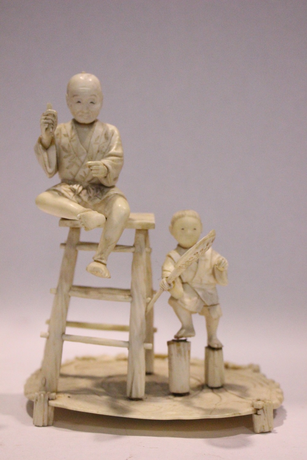 A JAPANESE CARVED FIGURAL GROUP, a man on a stool with a boy standing to his side, 6.75" tall approx - Image 2 of 7