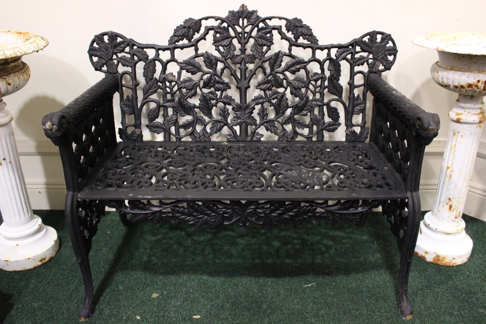 A PAIR OF CAST IRON GARDEN CHAIRS, with ram head arm rests, and foliage design to the back, 43" x