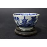 A SMALL CHINESE BLUE & WHITE BOWL, with images of pagodas and birds in flight, on a carved base,