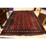 A GOOD QUALITY FLOOR RUG, with main ground colour red, 74" x 100" approx