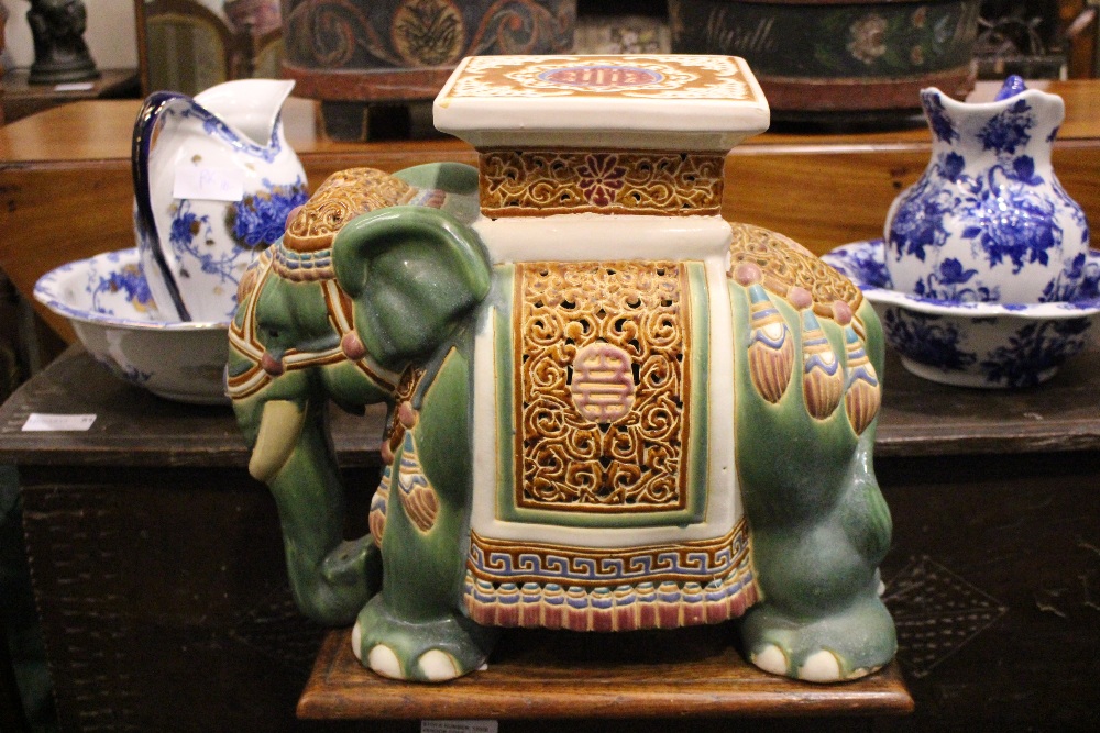 A CERAMIC JARDINERE / POT STAND IN THE FORM OF AN ELEPHANT, dressed in robes with a square seat as