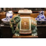 A CERAMIC JARDINERE / POT STAND IN THE FORM OF AN ELEPHANT, dressed in robes with a square seat as