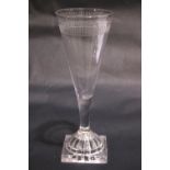 A TAPERED GLASS FLUTE, with cut detail to the rim, raised on a lemon squeeze foot / base, 7" tall